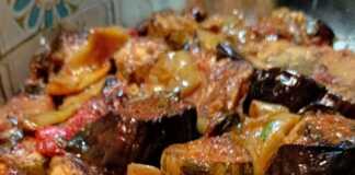 Ένα ταψί γεμάτο με πολύχρωμα ψητά λαχανικά, όπως κολοκυθάκια, μελιτζάνες, πατάτες και πιπεριές, αναμεμειγμένα με ζουμερές ροδισμένες πανσέτες χοιρινό.