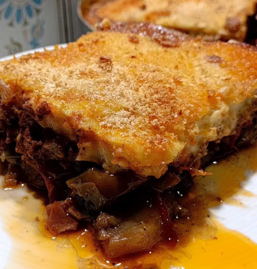 oikogeniakos mousakas Ένα κομμάτι με λαχταριστό, χρυσαφένιο μουσακά, έτοιμο να σερβιριστεί.