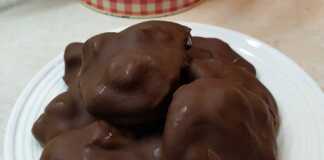 Λευκές μπουκίτσες παγωμένου γιαουρτιού με κομματάκια φρούτων, περιχυμένες με λιωμένη μαύρη σοκολάτα, τοποθετημένες σε λαδόκολλα.