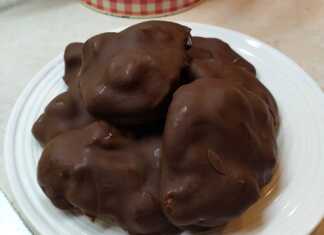 Λευκές μπουκίτσες παγωμένου γιαουρτιού με κομματάκια φρούτων, περιχυμένες με λιωμένη μαύρη σοκολάτα, τοποθετημένες σε λαδόκολλα.