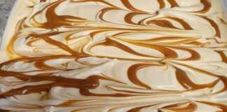 Ένα μπολ με παγωτό παρφέ καραμέλα, γαρνιρισμένο με σος καραμέλας και ίσως λίγα κομμάτια σοκολάτας, έτοιμο για σερβίρισμα.