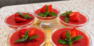 Πέντα γυάλινα ποτήρια με στρώσεις παννακότας (κάτω) και κόκκινου ζελέ φράουλας (πάνω), διακοσμημένα με φρέσκες φράουλες.