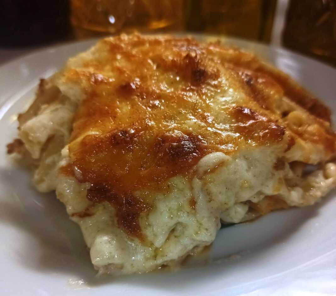pastitsio tis noikokyras Ένα κομμάτι χρυσαφένιο παστίτσιο, με αφράτη, ροδοκόκκινη μπεσαμέλ από πάνω.