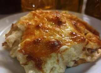 Ένα κομμάτι χρυσαφένιο παστίτσιο, με αφράτη, ροδοκόκκινη μπεσαμέλ από πάνω.