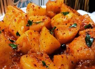 Πατάτες Γιαχνί: Απλά και Νόστιμα! Ένα πιάτο με ζεστές πατάτες γιαχνί, περιχυμένες με κόκκινη σάλτσα, πασπαλισμένες με μαϊντανό και μπούκοβο, με ένα κομμάτι φέτας στο πλάι.