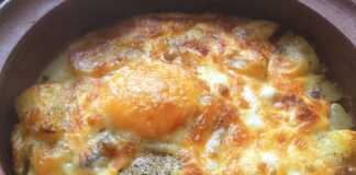 Ένα ταψί με χρυσαφένιες ψητές πατάτες, ανακατεμένες με τυρί, και δύο ολόκληρα αυγά στην επιφάνεια, ψημένα μέχρι να ροδίσουν.