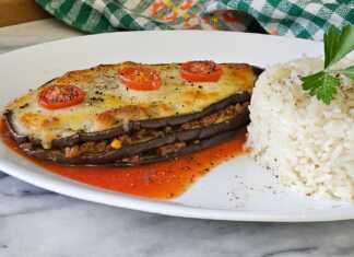 Ένα πιατο με ψητές μελιτζάνες γεμισμένες με κιμά και καλυμμένες με λιωμένη μοτσαρέλα και ντοματίνια, έτοιμες για σερβίρισμα.