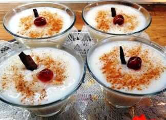 Ρυζόγαλο με Γεύση Βανίλια-Κανέλα Μπολάκια με ζεστό, κρεμώδες ρυζόγαλο πασπαλισμένο με κανέλα, τοποθετημένα σε ξύλινη επιφάνεια.