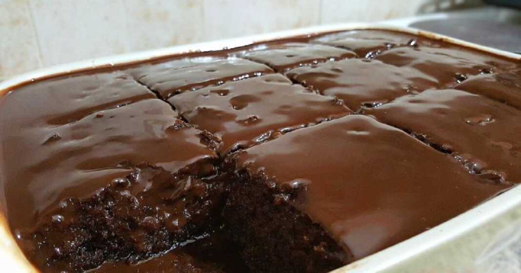 sokolatenio keik xoris kopo Ένα ολόκληρο, τετράγωνο σοκολατένιο κέικ με γυαλιστερό γλάσο σοκολάτας στην κορυφή, τοποθετημένο πάνω σε μια σχάρα για να κρυώσει.