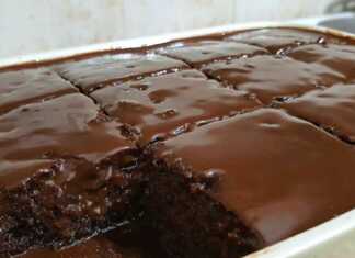 Ζουμερό σοκολατένιο κέικ σε τετράγωνα κομμάτια καλυμμένο με γυαλιστερό γλάσο κουβερτούρας και πασπαλισμένο με ξηρούς καρπούς