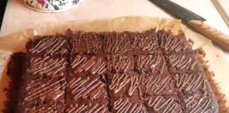 Ένα ταψί σοκολατένιου κέικ με κολοκυθάκι, με σκούρο καφέ χρώμα, γυαλιστερή επιφάνεια και ίχνη λιωμένης σοκολάτας από πάνω.