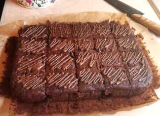 Ένα ταψί σοκολατένιου κέικ με κολοκυθάκι, με σκούρο καφέ χρώμα, γυαλιστερή επιφάνεια και ίχνη λιωμένης σοκολάτας από πάνω.