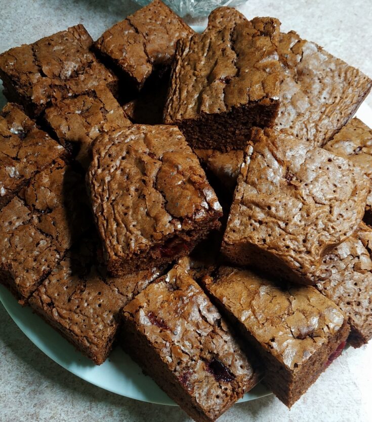 Κομμάτια από αφράτο σοκολατένιο πειρασμό με κεράσια, κομμένο σε τετράγωνο σχήμα, που φαίνονται τα κεράσια μέσα στη ζύμη.