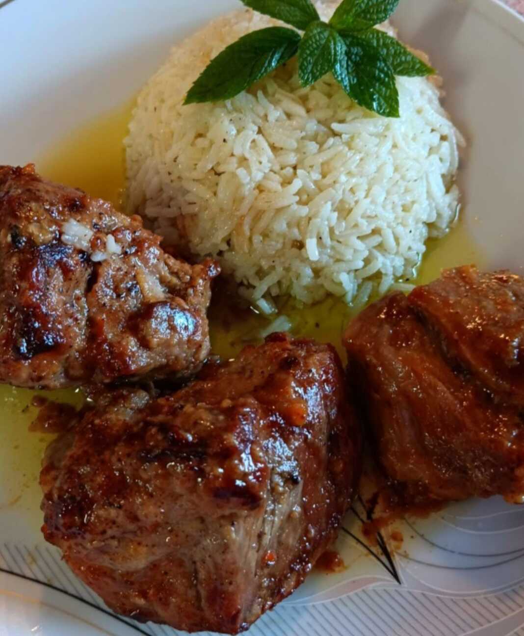 Ένα ταψί με κομμάτια ψητού χοιρινού που έχουν ροδίσει ωραία, σερβιρισμένα δίπλα σε ένα μπολ με λευκό ρύζι μπασμάτι.