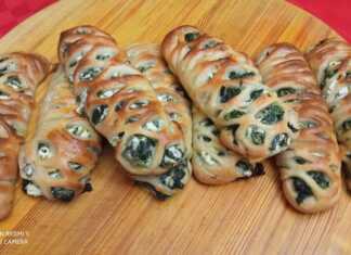 Εξι χρυσαφένια, φρεσκοψημένα σπανακοπιτάκια σε σχήμα πλεξούδας, τοποθετημένα σε λαδόκολλα, με ελαφρώς εμφανή τη γέμιση.