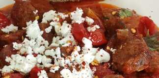 Ένα πιατο γεμάτο με κόκκινο, ζουμερό σπετσοφάι, με κομμάτια λουκάνικου, πιπεριές και ντομάτα.