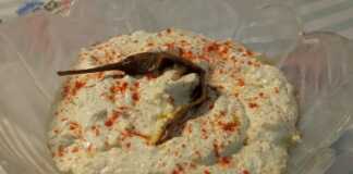 Ένα μπολ με λευκή, κρεμώδη σπιτική τυροκαυτερή, πασπαλισμένη με κόκκινη πάπρικα και γαρνιρισμένη με μια ολόκληρη πιπεριά τσίλι.