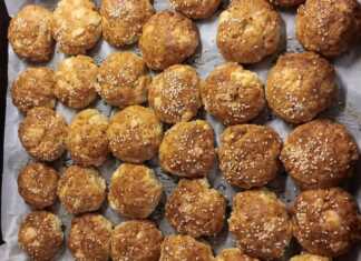 Ένα ταψί γεμάτο με χρυσαφένια, στρογγυλά τυροπιτάκια φούρνου, πασπαλισμένα με σουσάμι, έτοιμα να σερβιριστούν.