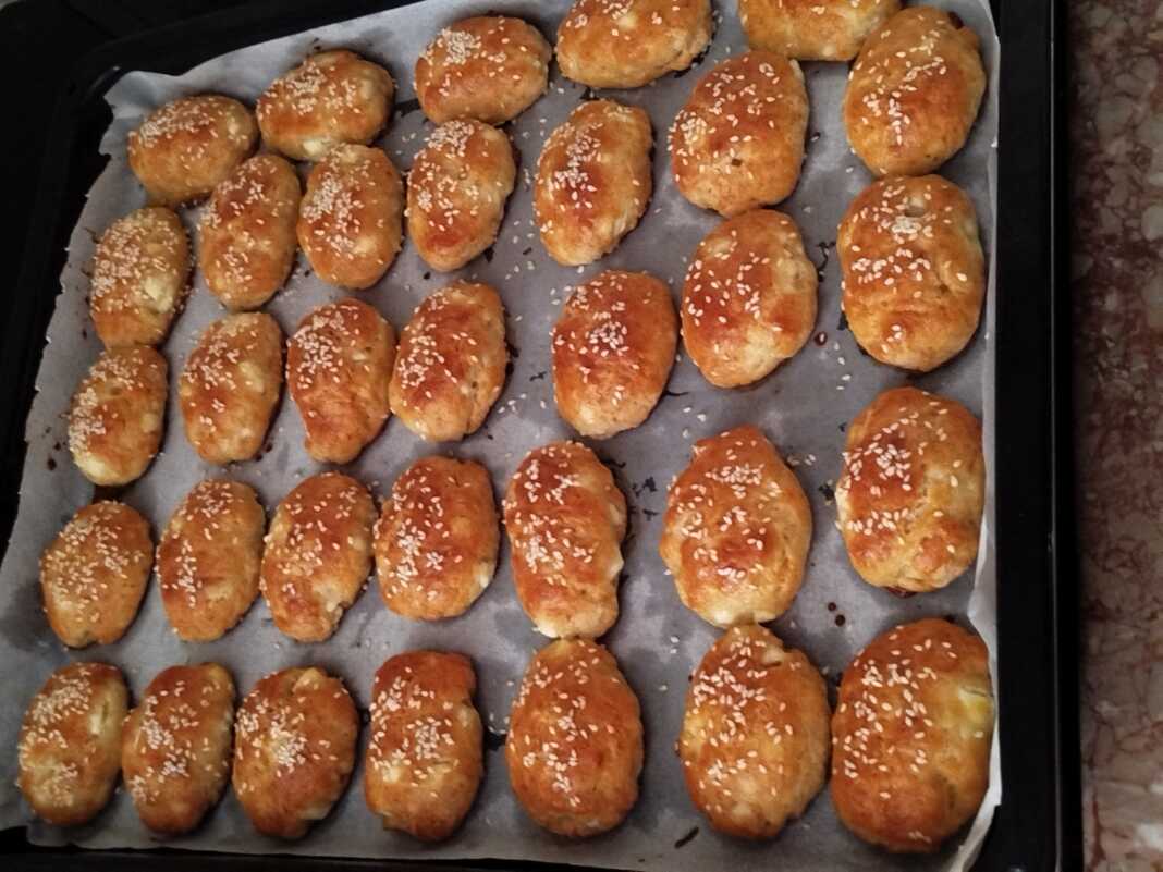 tiropitakia koutou Ένα ταψί γεμάτο με χρυσαφένια, αφράτα τυροπιτάκια κουρού, πασπαλισμένα με σουσάμι, φρεσκοψημένα.