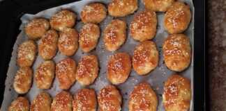 Ένα ταψί γεμάτο με χρυσαφένια, αφράτα τυροπιτάκια κουρού, πασπαλισμένα με σουσάμι, φρεσκοψημένα.