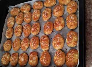 Ένα ταψί γεμάτο με χρυσαφένια, αφράτα τυροπιτάκια κουρού, πασπαλισμένα με σουσάμι, φρεσκοψημένα.