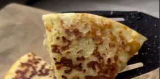 Λαχταριστή τηγανίτα με τυριά σε πιάτο, κομμένη σε κομμάτια, με λιωμένο βούτυρο στην επιφάνεια.