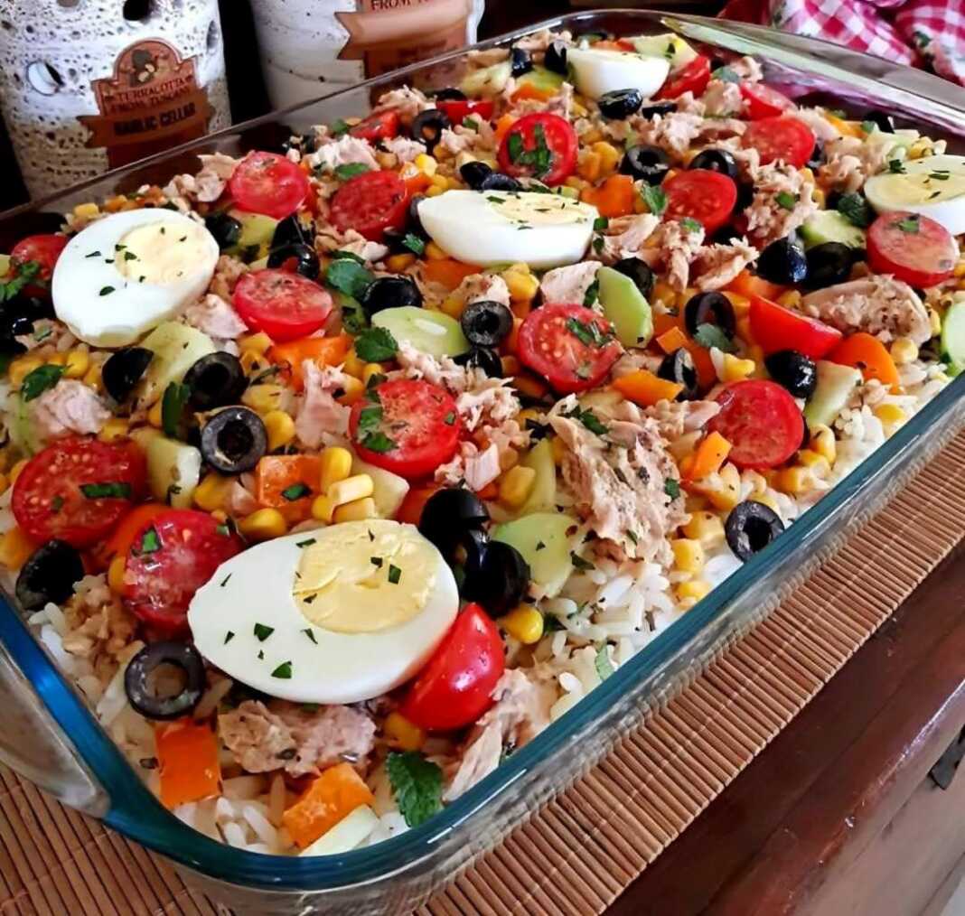 Μια μεγάλη πιατέλα γεμάτη με πολύχρωμη τονοσαλάτα ρυζιού, με κομμάτια τόνου, ντοματίνια, ελιές, καλαμπόκι, πιπεριές και φρέσκα μυρωδικά.