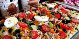 Μια μεγάλη πιατέλα γεμάτη με πολύχρωμη τονοσαλάτα ρυζιού, με κομμάτια τόνου, ντοματίνια, ελιές, καλαμπόκι, πιπεριές και φρέσκα μυρωδικά.