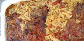 Ένα ταψί με λαχταριστό γιουβέτσι, με χρυσαφένιο κριθαράκι και κομμάτια χοιρινού κρέατος μέσα σε κόκκινη σάλτσα ντομάτας.