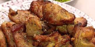 Μια μερίδα Χοιρινή τηγανιά με ροδισμένα κομμάτια κρέατος σε ένα πιάτο, με πράσινη σαλάτα στο πλάι.