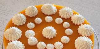 Ένα ολόκληρο τσιζκέικ χωρίς ψήσιμο με ροδάκινα, γαρνιρισμένο με σαντιγί, έτοιμο για σερβίρισμα.