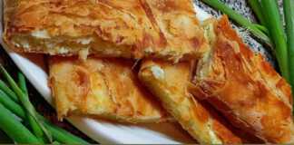 Ηπειρώτικη Ριζοτυρόπιτα Κοντινό πλάνο σε ένα κομμάτι Ηπειρώτικης Ριζοτυρόπιτας, που αναδεικνύει τις στρώσεις του φύλλου και την πλούσια γέμιση ρυζιού και φέτας."