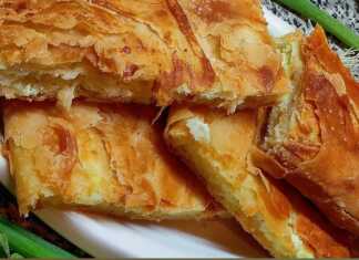 Κοντινό πλάνο σε ένα κομμάτι Ηπειρώτικης Ριζοτυρόπιτας, που αναδεικνύει τις στρώσεις του φύλλου και την πλούσια γέμιση ρυζιού και φέτας."