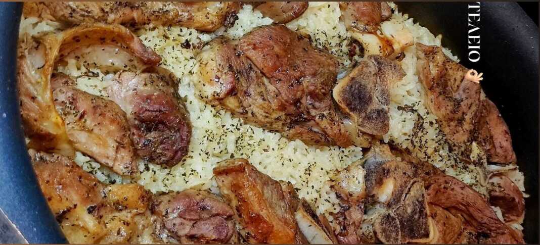 Αρνάκι με ρύζι στη γάστρα, φρεσκοψημένο, με λεμόνι και φρέσκο κρεμμυδάκι για σερβίρισμα.