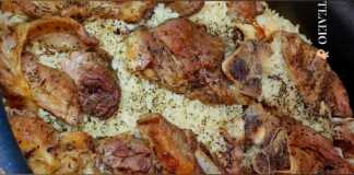 Αρνάκι με ρύζι στη γάστρα, φρεσκοψημένο, με λεμόνι και φρέσκο κρεμμυδάκι για σερβίρισμα.