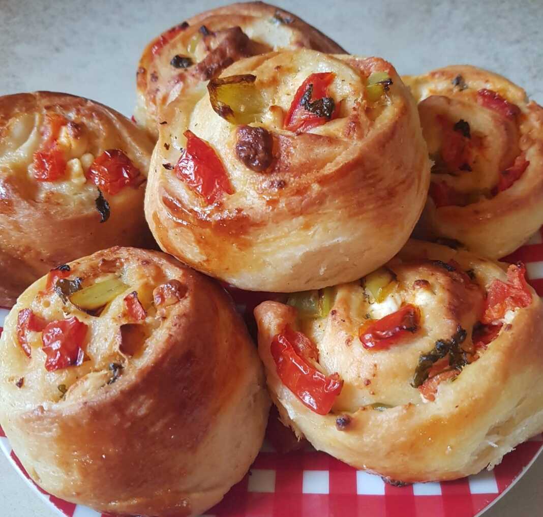 Κομμένο ατομικό πιτσάκι προζύμι, με ορατή τη γέμιση από φέτα, πιπεριά και ντομάτα.