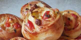 Κομμένο ατομικό πιτσάκι προζύμι, με ορατή τη γέμιση από φέτα, πιπεριά και ντομάτα.