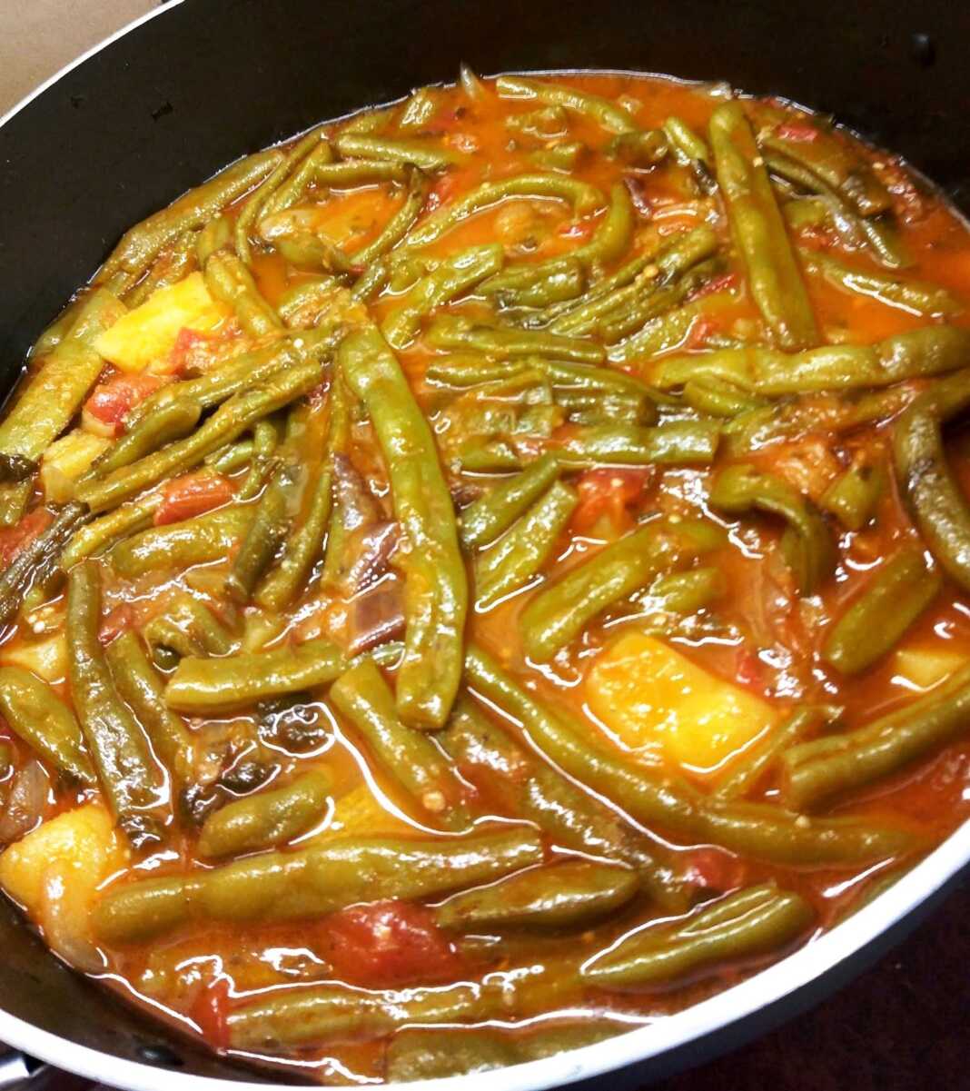 fasolakia melitzana Μία κατσαρόλα με λαχταριστά φασολάκια με μελιτζάνες, πλούσια κόκκινη σάλτσα, έτοιμο για σερβίρισμα.