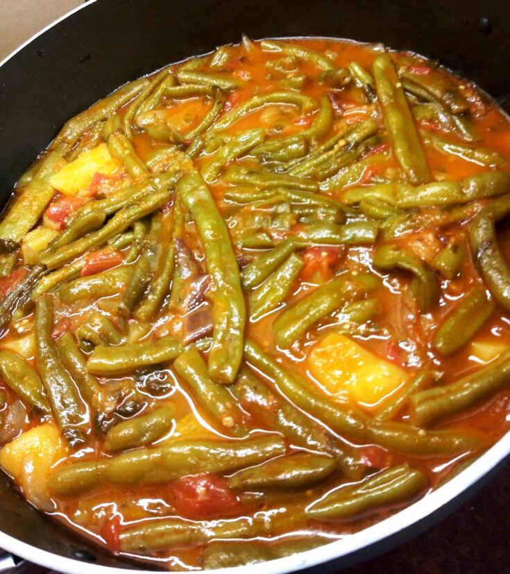 Μία κατσαρόλα με λαχταριστά φασολάκια με μελιτζάνες, πλούσια κόκκινη σάλτσα, έτοιμο για σερβίρισμα.