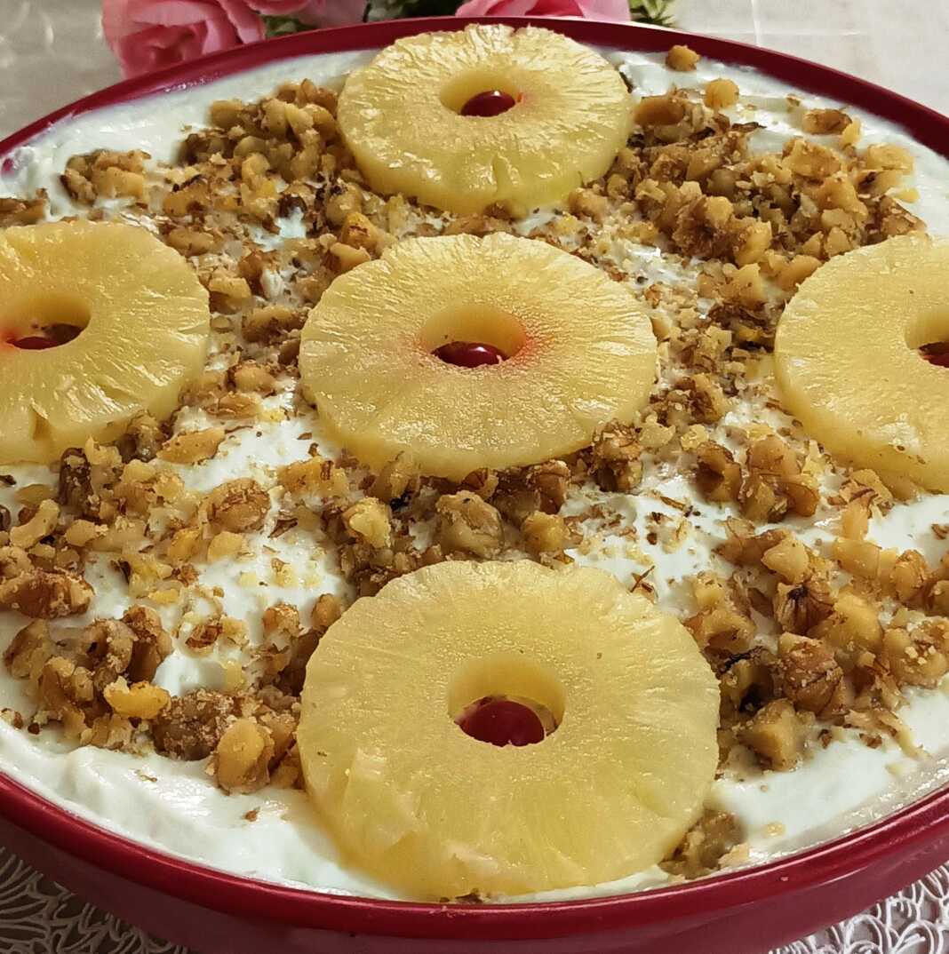 giaourtokliko me anana Ενα ταψί με δροσερό γλυκό γιαούρτι με κομματάκια ανανά, πασπαλισμένο με καρύδια, έτοιμο για σερβίρισμα.