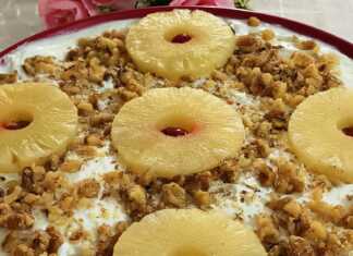 Ενα ταψί με δροσερό γλυκό γιαούρτι με κομματάκια ανανά, πασπαλισμένο με καρύδια, έτοιμο για σερβίρισμα.