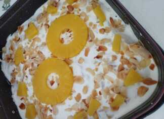 Ένα ολόκληρο Δροσερό Γλυκό με Ανανά, διακοσμημένο με ροδέλες ανανά και φιλέ αμυγδάλου, σε μία πιατέλα.