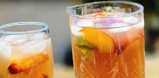 2 ποτήρια με χειροποίητο παγωμένο τσάι ροδάκινο, φέτες λάιμ και παγάκια.