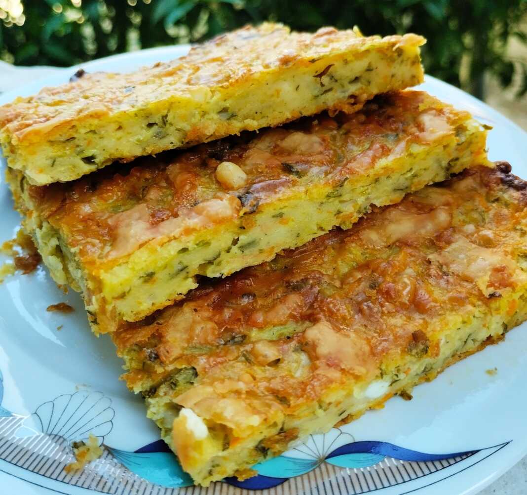 kolokithopita xoris filo Παραδοσιακή κολοκυθόπιτα χωρίς φύλλο (μπατζίνα), κομμένη σε κομμάτια σε πιάτο.