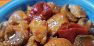 Πιάτο με Κοτόπουλο στήθος με μανιτάρια και πιπεριές Φλωρίνης σε πλούσια κόκκινη σάλτσα, έτοιμο για σερβίρισμα.
