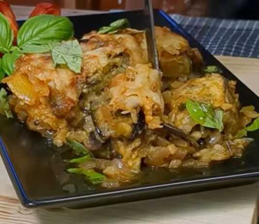 Κοντινό πλάνο σε μια μερίδα Μελιτζάνες με Λουκάνικο στο Φούρνο, που αναδεικνύει τις στρώσεις και τη χρυσαφένια κρούστα τυριού.