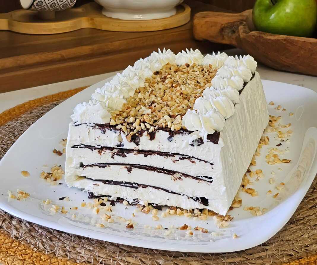 Ένα ολόκληρο Παγωτό Σοκολάτας με Στρώσεις, σε πιατέλα, διακοσμημένο με κρέμα, σιρόπι σοκολάτας και φουντούκια