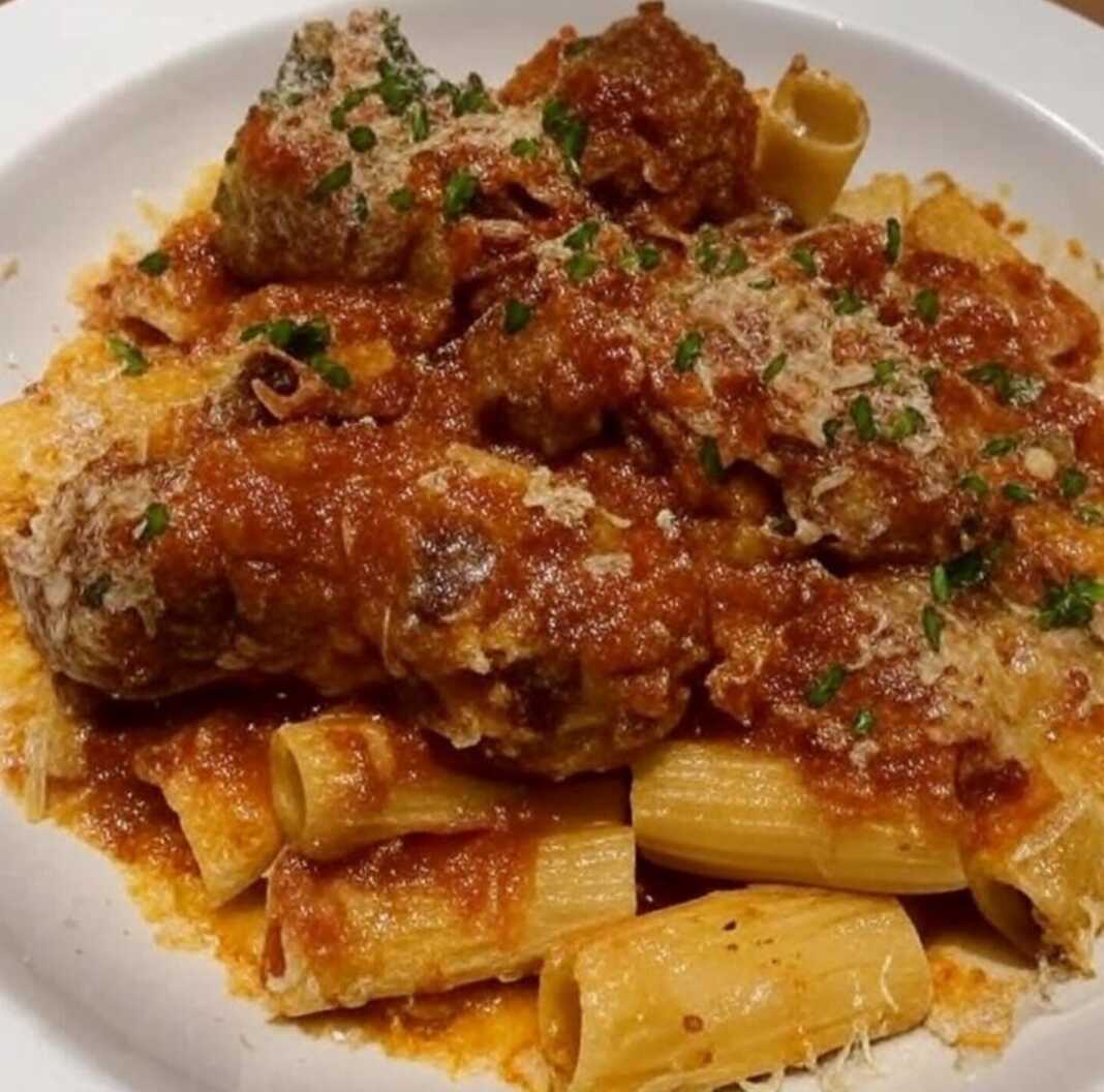 Ένα πιάτο Ριγκατόνι με Κεφτεδάκια με πλούσια σάλτσα ντομάτας, γαρνιρισμένο με βασιλικό