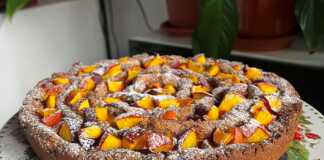 Μία ολόκληρη Σπιτική Γλυκιά Πίτα με Ροδάκινα, πασπαλισμένη με άχνη ζάχαρη, έτοιμη να κοπεί.