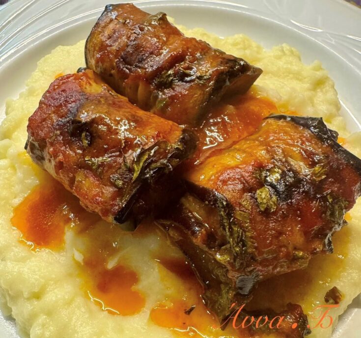 Ζουμερά ρολάκια μελιτζάνας με κιμά σε σάλτσα ντομάτας, συνοδευόμενα από αφράτο πουρέ πατάτας.